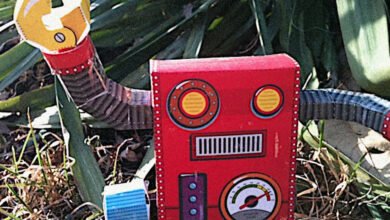 A red papercraft robot with yellow gear hands