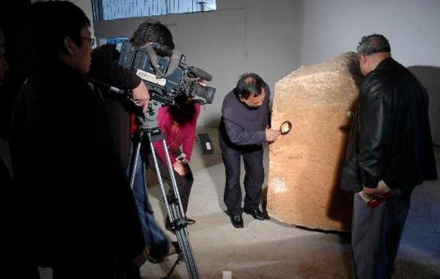 Chinese archaeologists investigate an ancient block of stone